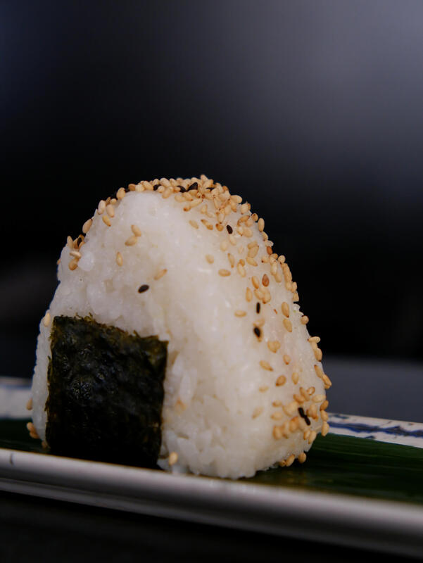 Sushi Onigiri, polpetta di riso con al suo interno avocado e salmone crudo. sopra sesamo